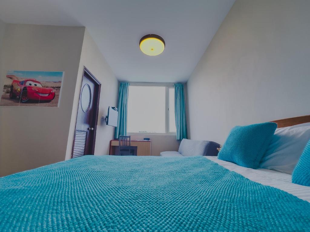 una camera da letto con un letto con lenzuola blu e una finestra di 炎島 & 莎蔓民宿Salman a Green Island