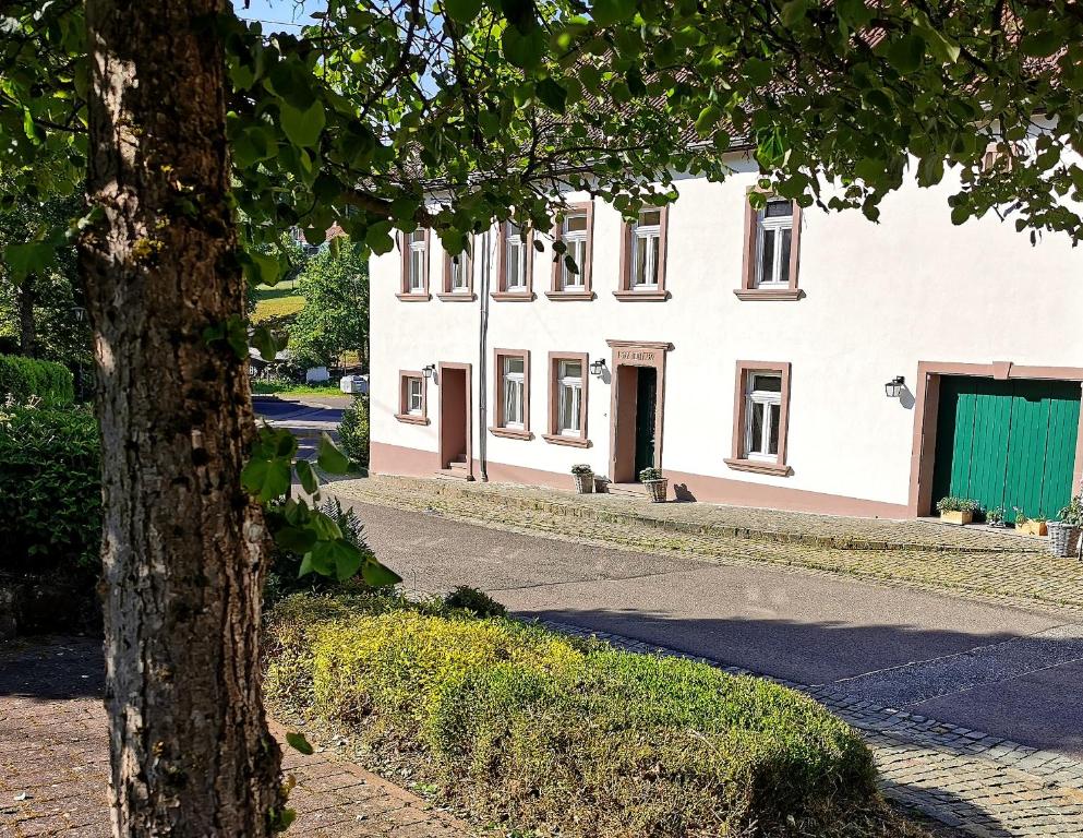 a white building with a green door next to a tree at Die Ferienwohnungen Schmiede und Gudd Stuvv in Annis Haus in Wadern