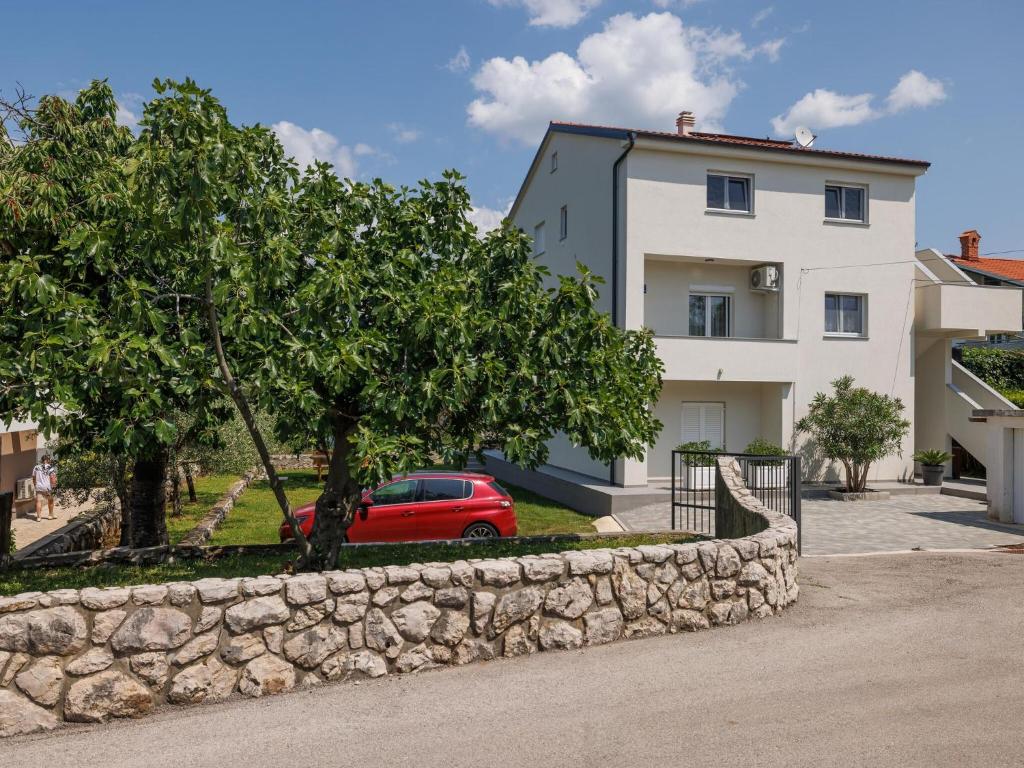 a red car parked in front of a white house at Apartment in ilo on Krk Island in Šilo