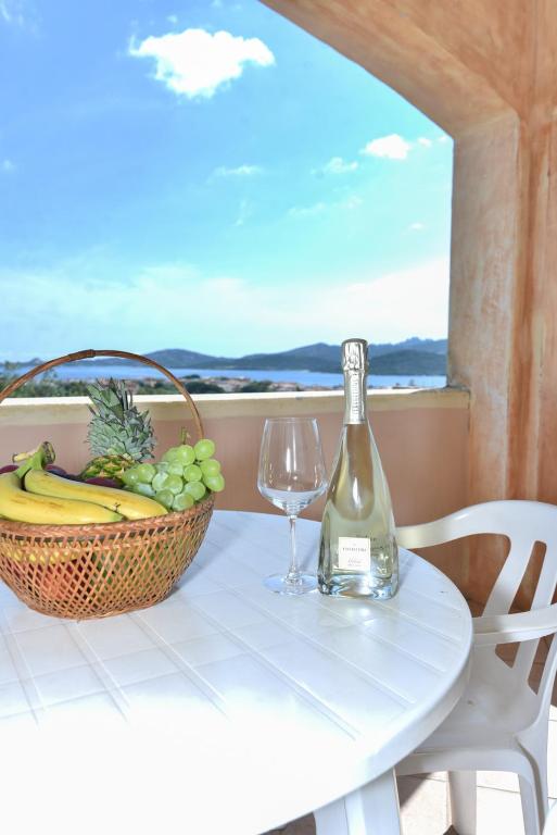 a table with a bottle of wine and a basket of fruit at La Costa View in Arzachena