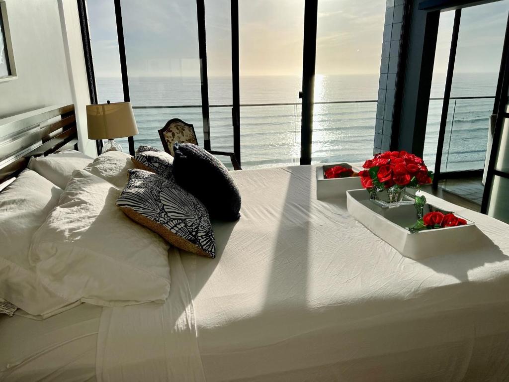 Ocean View Luxury Condo Oceanfront and Pool في سان دييغو: سرير أبيض كبير في غرفة بها نوافذ