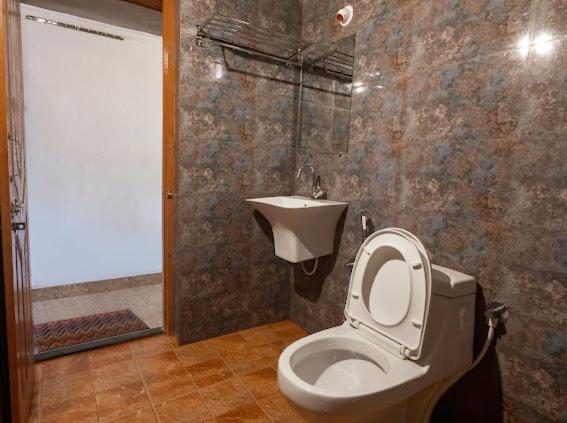 un baño con inodoro y lavabo en Taya Beach Front, en Gokarna