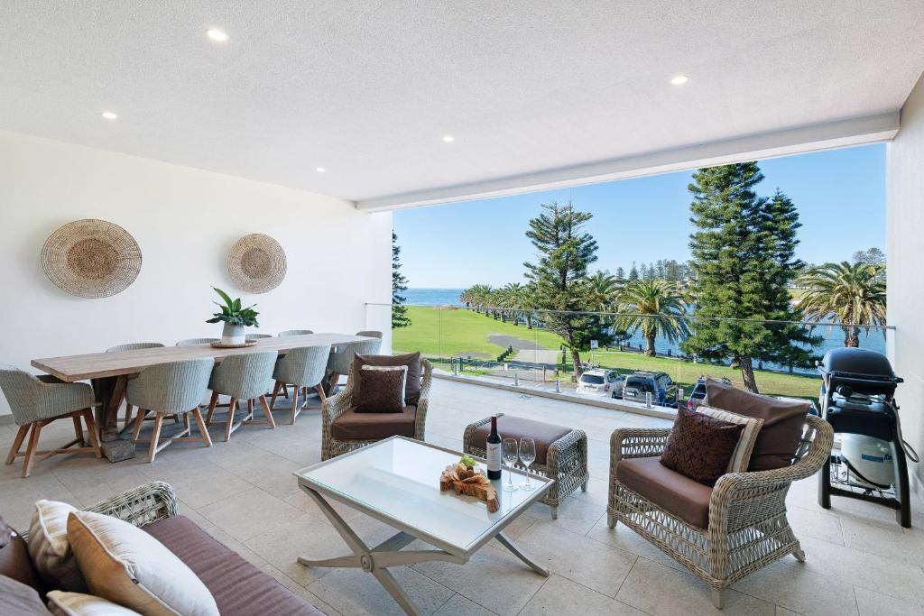 a living room with a table and chairs and a large window at Kiama Waterfront Apartment in Kiama