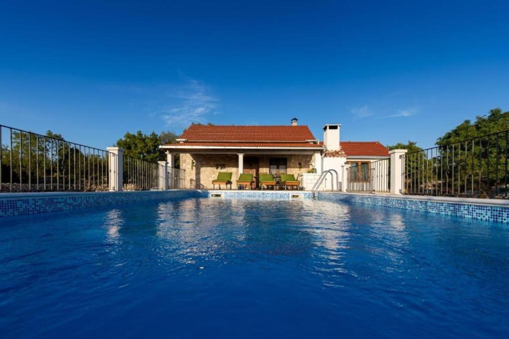 ein Haus mit einem Pool vor einem Zaun in der Unterkunft Villa Menalo in Neum