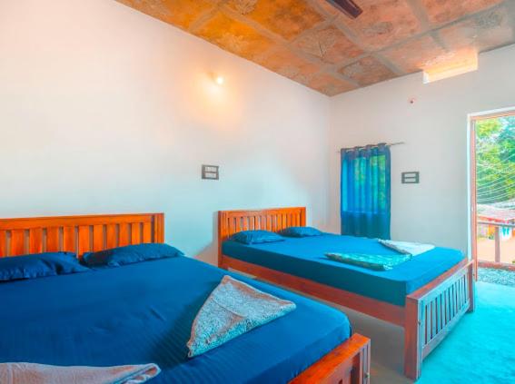 2 camas en un dormitorio con sábanas azules y ventana en Taya Beach Front, en Gokarna