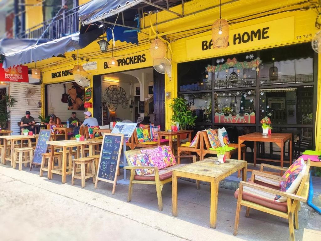 a group of tables and chairs outside of a restaurant at Back Home Backpackers Hostel in Bangkok