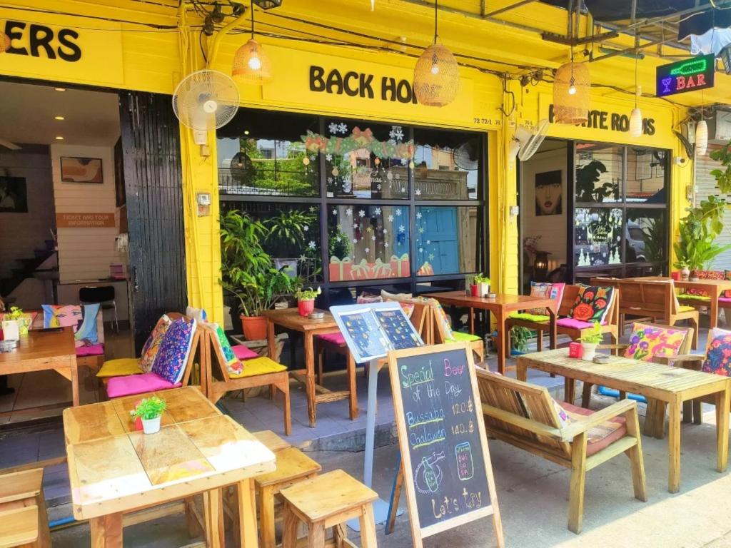 restauracja z drewnianymi stołami i krzesłami oraz tablicą w obiekcie Back Home Backpackers w mieście Bangkok