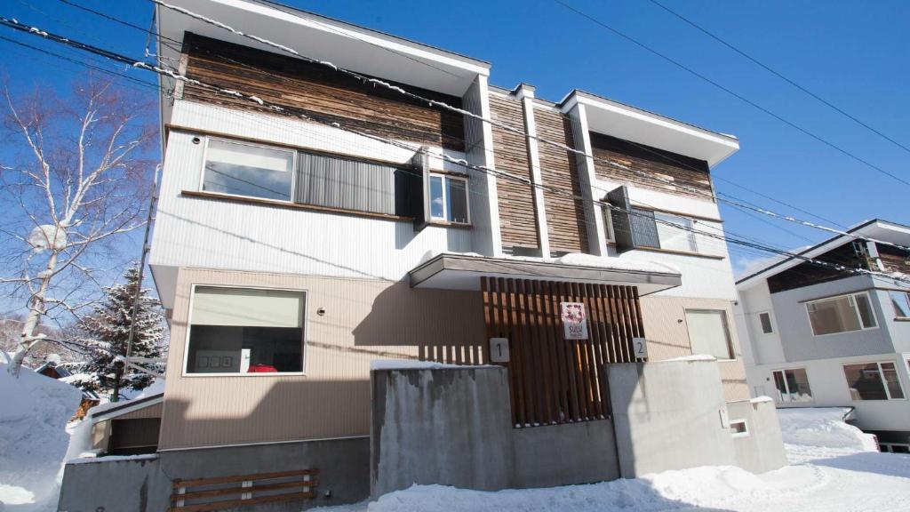 a building with snow in front of it at Itoku in Niseko