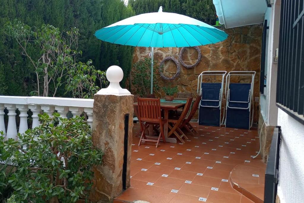 un patio con una mesa y una sombrilla azul en Casa Tena en La Cañada