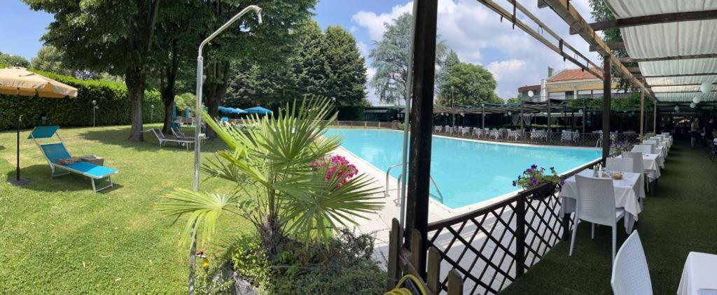 a swimming pool with tables and chairs in a yard at Hotel Sporting Brugherio in Brugherio