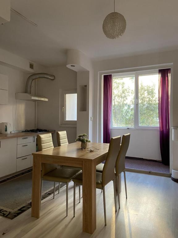 Una cocina y un comedor con mesa y sillas de madera. en Bucharest Trip Apartment, en Bucarest