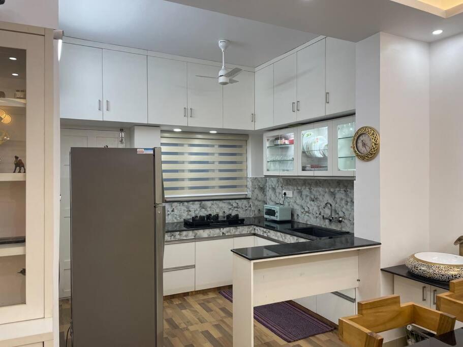 a kitchen with white cabinets and a stainless steel refrigerator at Second home International airport T-1 in Trivandrum