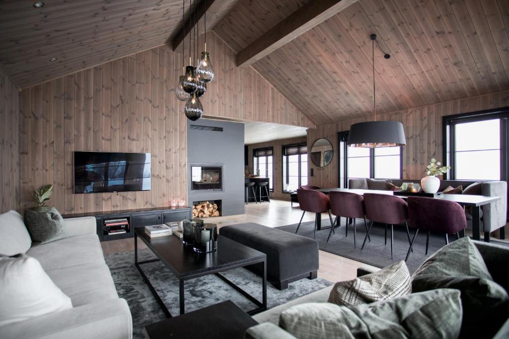 un soggiorno con divano e tavolo di Strandafjellet Panorama Lodge - Large Cabin with Majestic Mountain View a Stranda