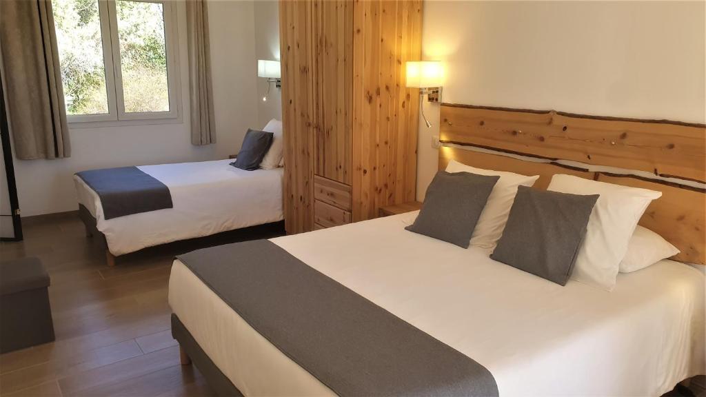 a hotel room with two beds and two windows at Lou Pic au Loup - Gîte Loup in Cazevieille