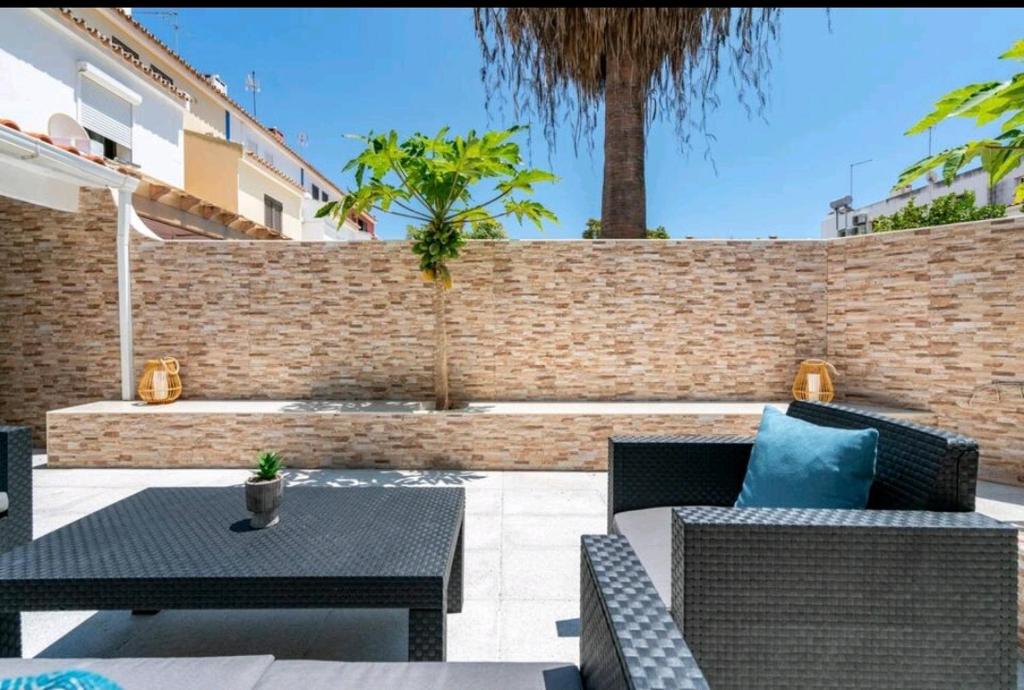a patio with chairs and tables and a brick wall at Marina Holiday House in Quarteira