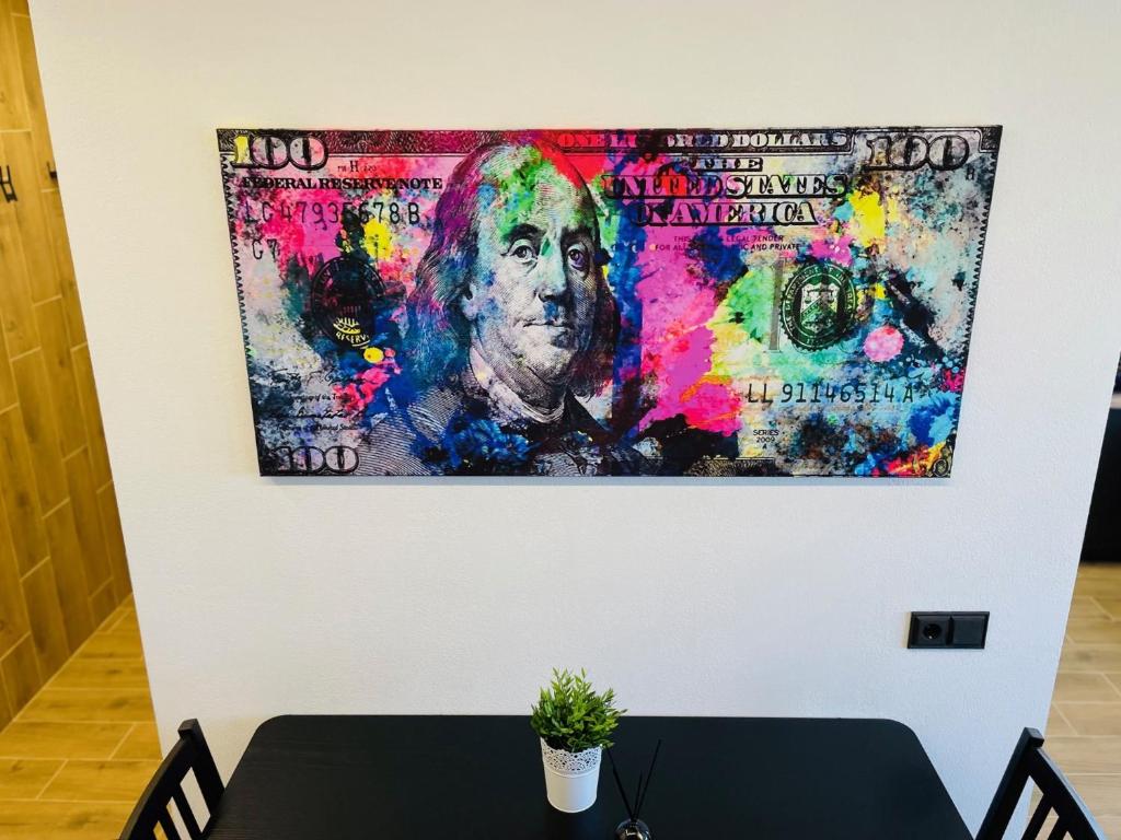 a painting hanging on a wall with a table at Alto Turtas Apartamentai in Šiauliai