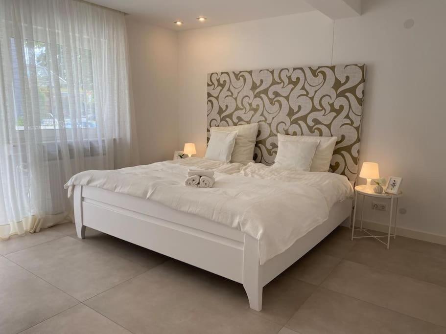 a bedroom with a large white bed with a headboard at Edles Apartment in Hanau mit Balkon und Freisitz, Pkw-Stellplatz in Hanau am Main