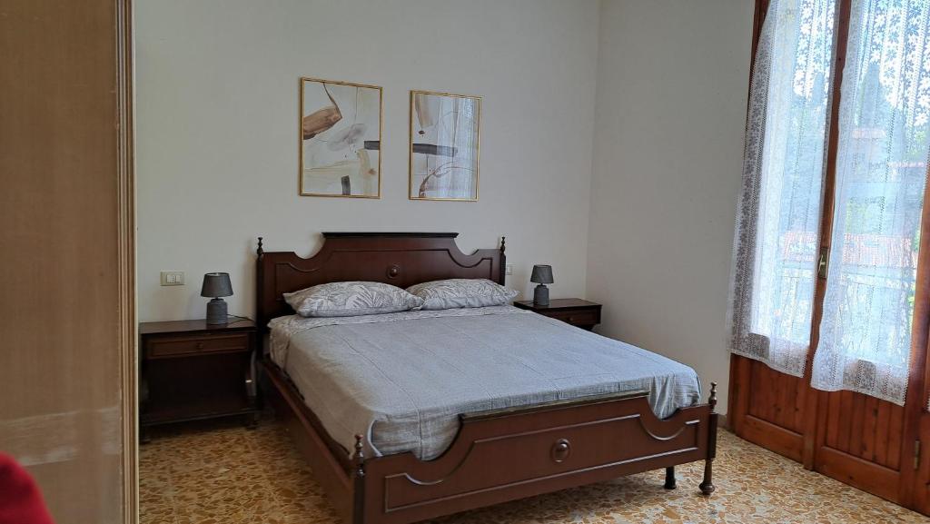 ein Schlafzimmer mit einem Bett mit zwei Nachttischen und zwei Fenstern in der Unterkunft Da Olga e Giubbino - Terrossola in Bibbiena