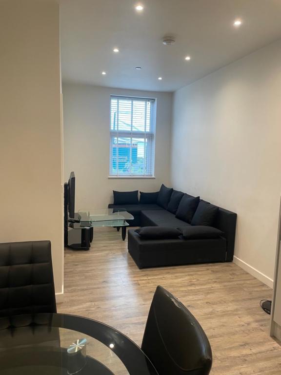 sala de estar con sofá negro y mesa de cristal en 1 bed apartment in the heart of Staines town centre, en Staines upon Thames