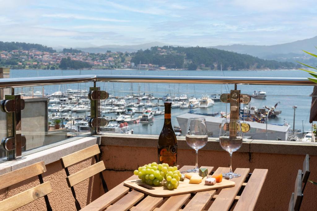 una mesa con copas de vino y uvas en el balcón en Combarro Playa, en Combarro