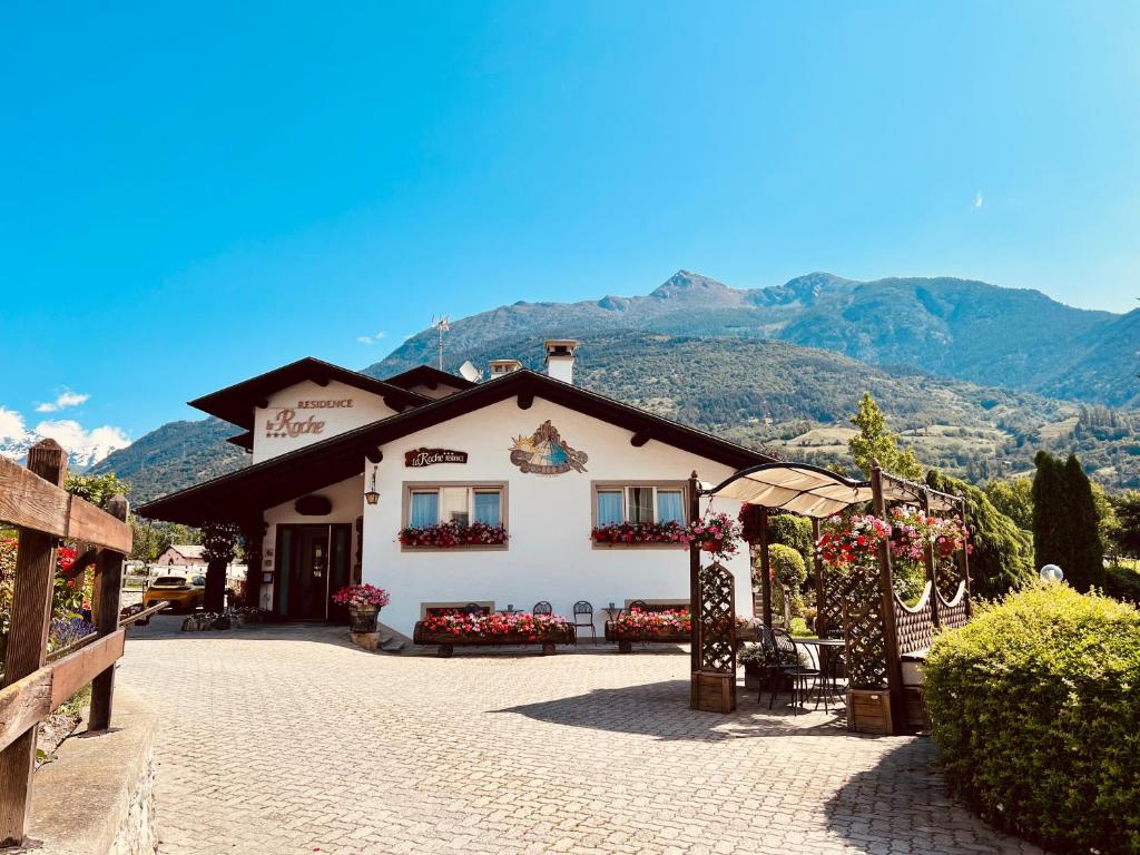 een wit gebouw met bloemen vooraan bij La Roche Hotel Appartments in Aosta