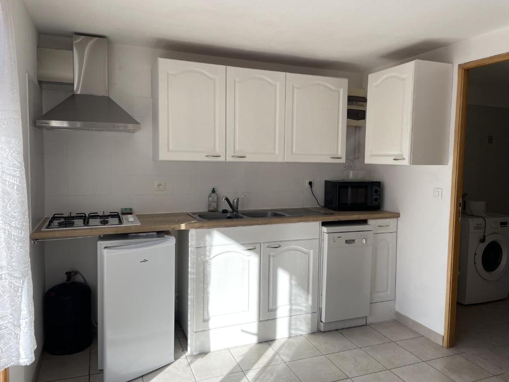 a kitchen with white cabinets and a counter top at Appartemant La Gardette in Le Puys