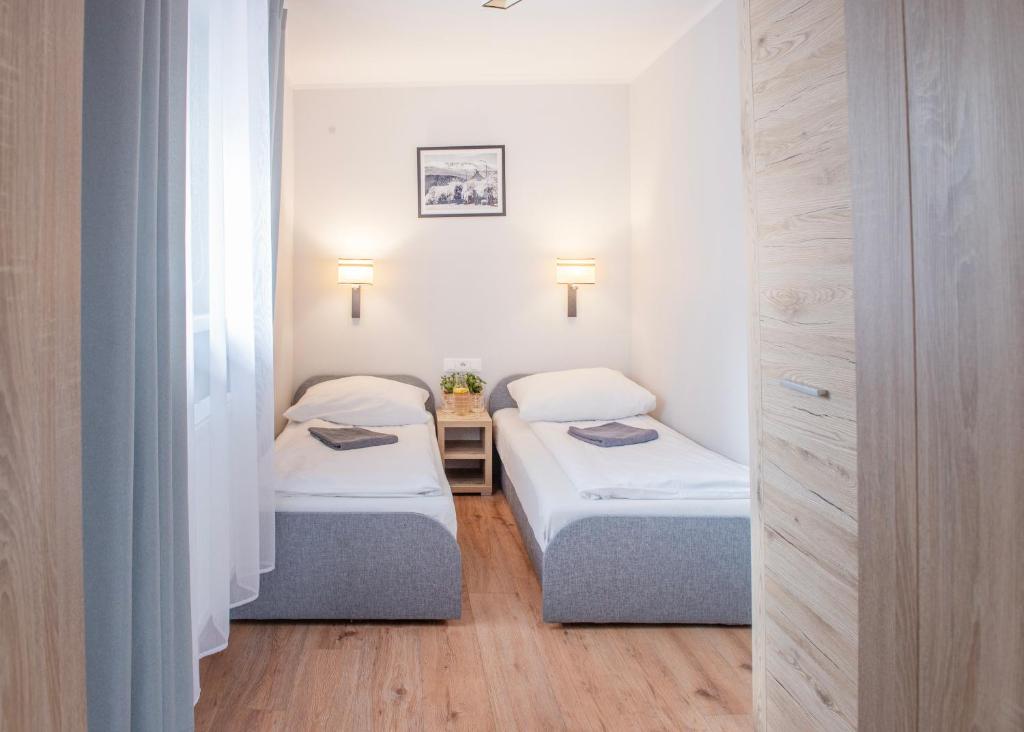 シュクラルスカ・ポレンバにあるWilla Izabelaの白い壁の客室で、ツインベッド2台が備わります。