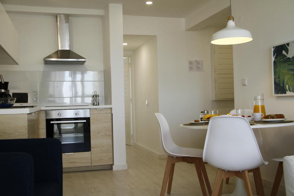 a kitchen with a table and white chairs in a room at Caparica Sea View Apt by be@home in Costa da Caparica