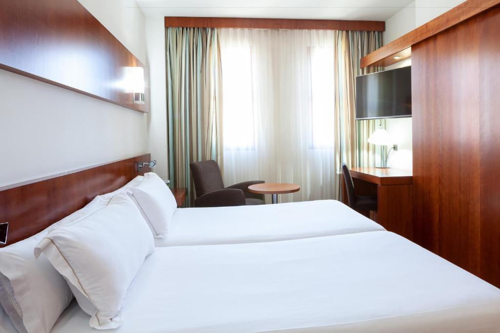 a hotel room with two beds and a television at Senator Huelva in Huelva