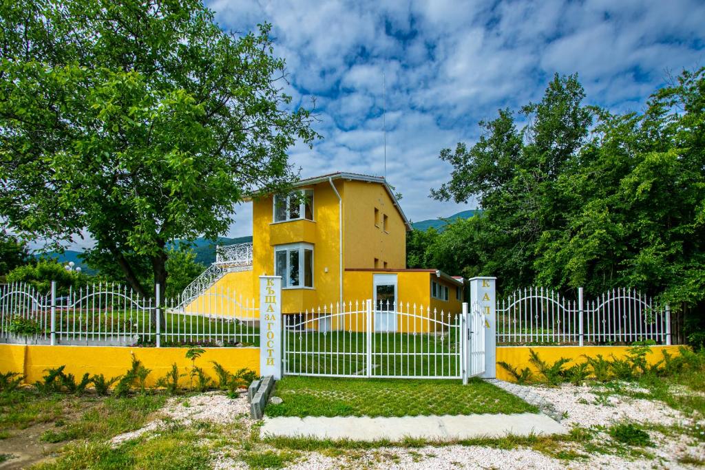 a yellow house with a fence in front of it at Къща за гости Кала in Patalenitsa