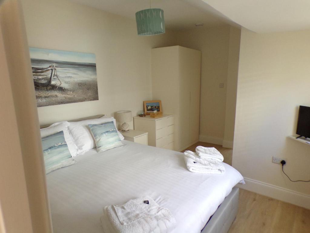 a bedroom with a white bed with towels on it at 3TheDome - Luxury Ground Floor Apartment opposite the Beach, Barton on Sea in Barton on Sea