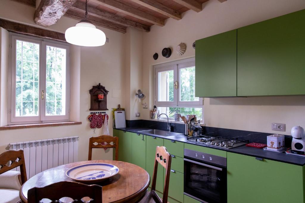 una cocina con armarios verdes y una mesa pequeña con mesa en Casa nella campagna Parmigiana. en Stradella