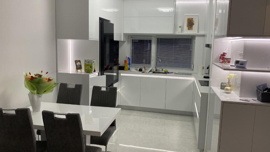 a white kitchen with a white table and chairs at Casa Andra in Dumbrăviţa