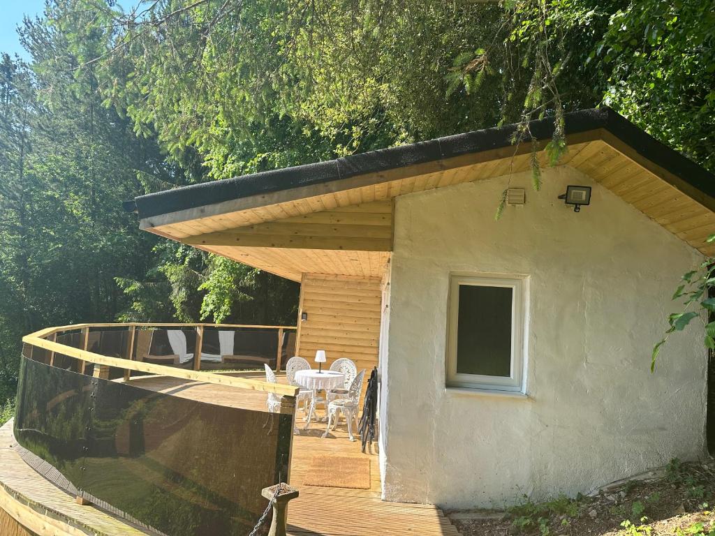een klein huis met een terras met een tafel en stoelen bij Unique Orchard Lodge for couples with hot tub in Strathaven