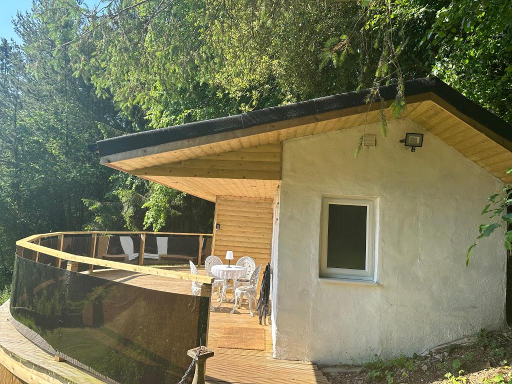 a small house with a deck with a table and chairs at Unique Orchard Lodge for couples with hot tub in Strathaven