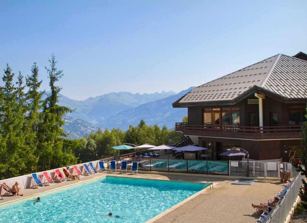 une piscine dans un complexe avec des montagnes en arrière-plan dans l'établissement VVF La Plagne Montalbert Paradiski, à Aime La Plagne