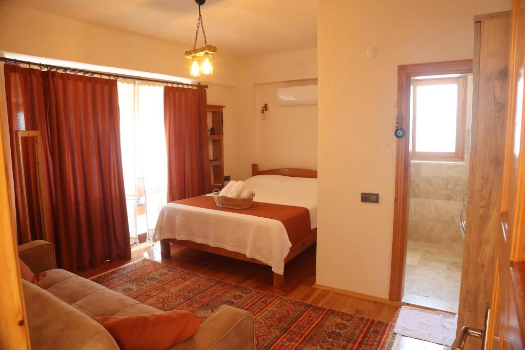 a bedroom with a bed and a couch and a window at Istlada Taş Ev Apart - Kekova View in Antalya
