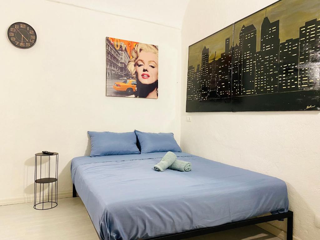 1 dormitorio con 1 cama con sábanas azules y reloj en Gilli Suite Sanremo, en San Remo