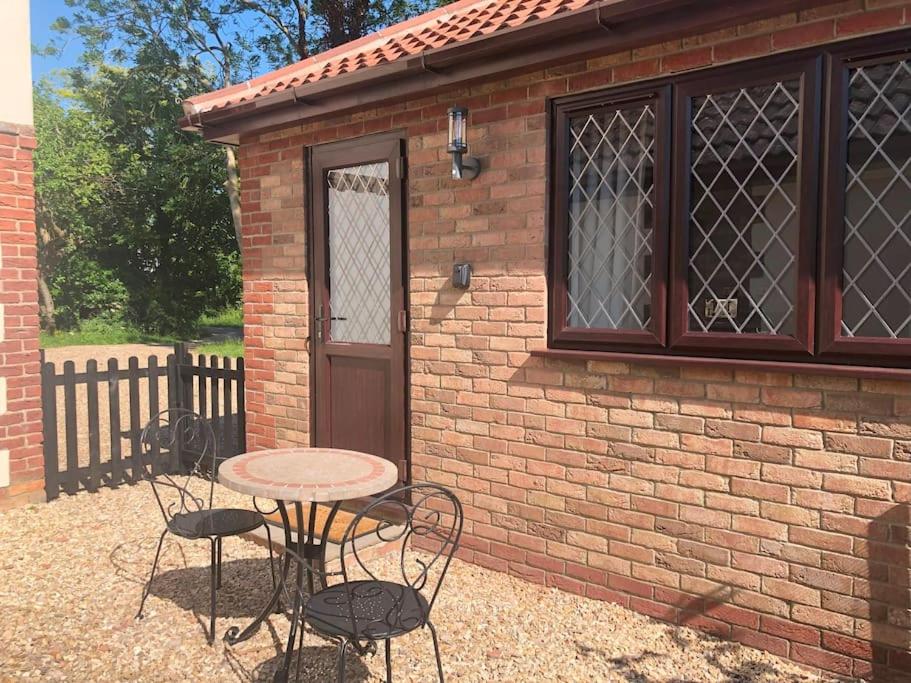 a table and chairs in front of a brick building at Ash Cottage in Skegness