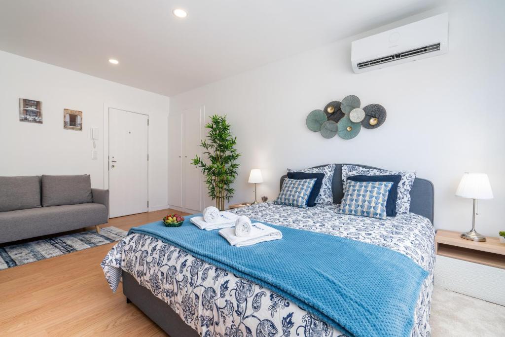 um quarto com uma cama com um cobertor azul e um sofá em Comfy Sunny Flat - Prime Location em Porto