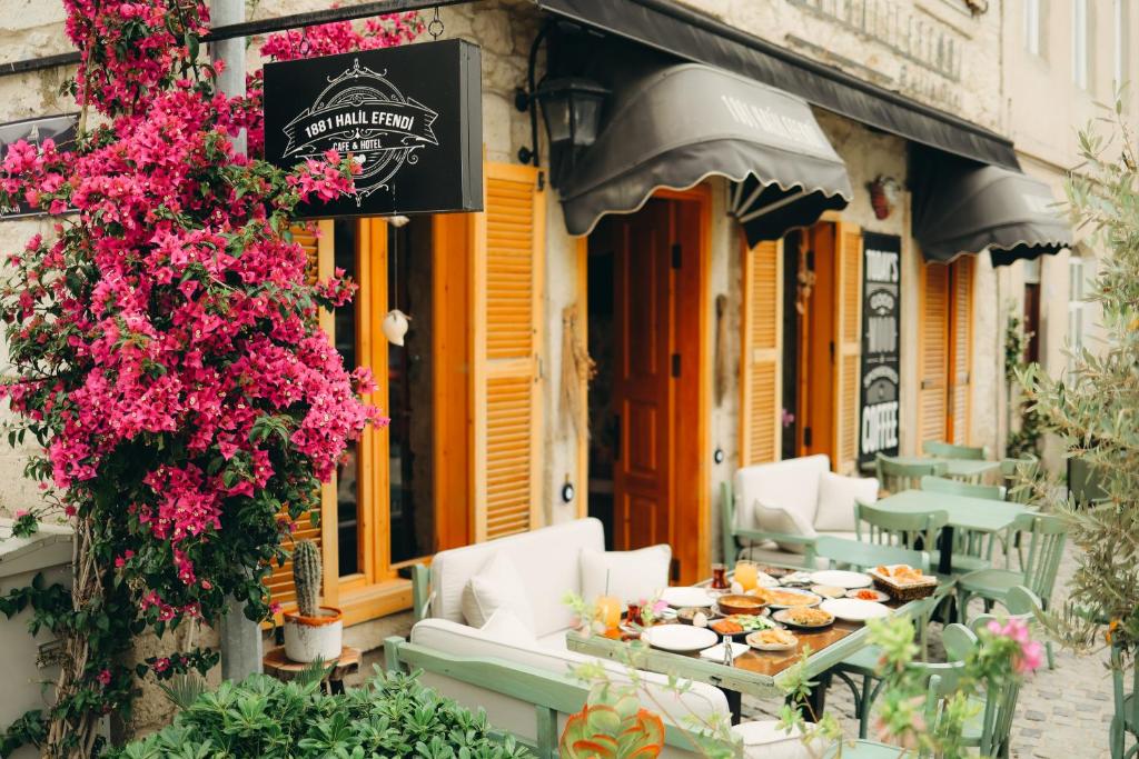 einen Tisch und Stühle außerhalb eines Restaurants mit Blumen in der Unterkunft 1881 HALİL EFENDİ OTEL in Alacati