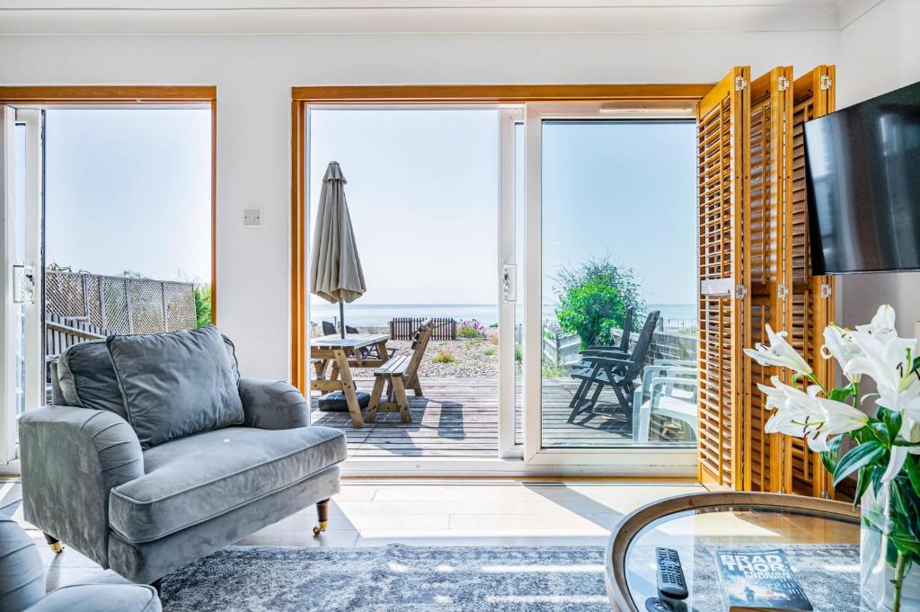 ein Wohnzimmer mit einem Stuhl und einer Glasschiebetür in der Unterkunft Pebble Paradise Beachfront Family Getaway in Pevensey