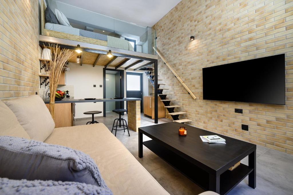 a living room with a couch and a tv on a brick wall at Loft 2 in Kos