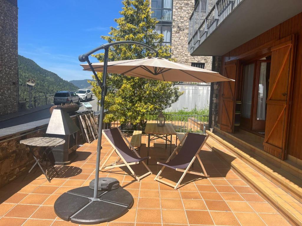 a patio with chairs and an umbrella on a balcony at Cap del Tarter Apartament in El Tarter