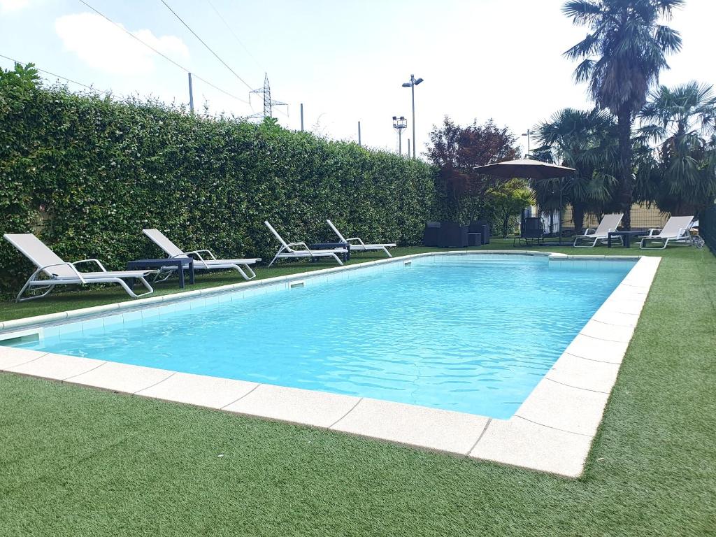 a swimming pool with lounge chairs on the grass at RipamontiBnB in Milan