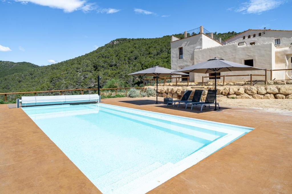 uma piscina com duas cadeiras e guarda-sóis em Cal Noia Villa 3 em Castellví de la Marca