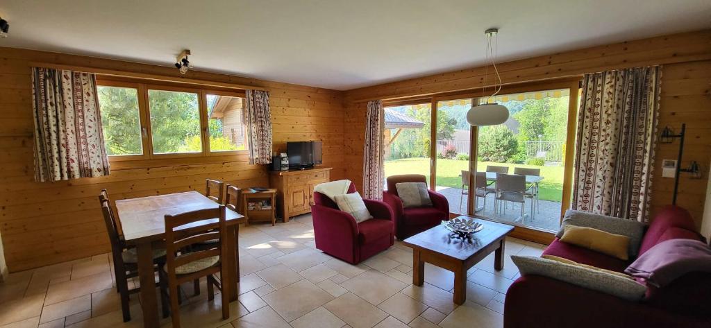 a living room with a couch and a table and chairs at RHODOS, Confort et Espace in Ovronnaz