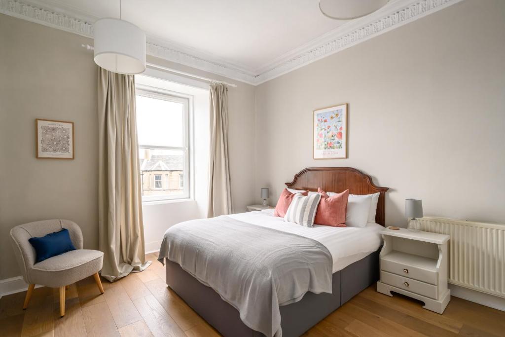 una camera con un letto e una sedia e una finestra di 2BR New Town Castle View Apartment a Edimburgo