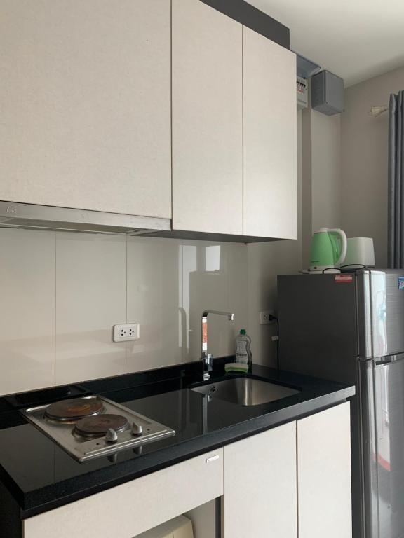 a kitchen with white cabinets and a sink and a refrigerator at Base Condos in Pattaya South