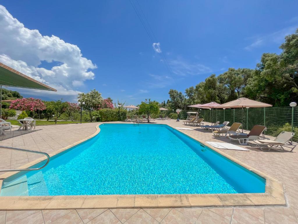 una piscina con sedie e ombrelloni accanto al resort di Amazona Apartments and Studios a Spartià